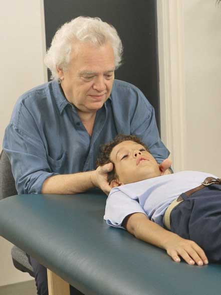 Il Dr. John E. Upledger, fondatore della Terapia Craniosacrale, mentre tratta un bambino durante una sessione
