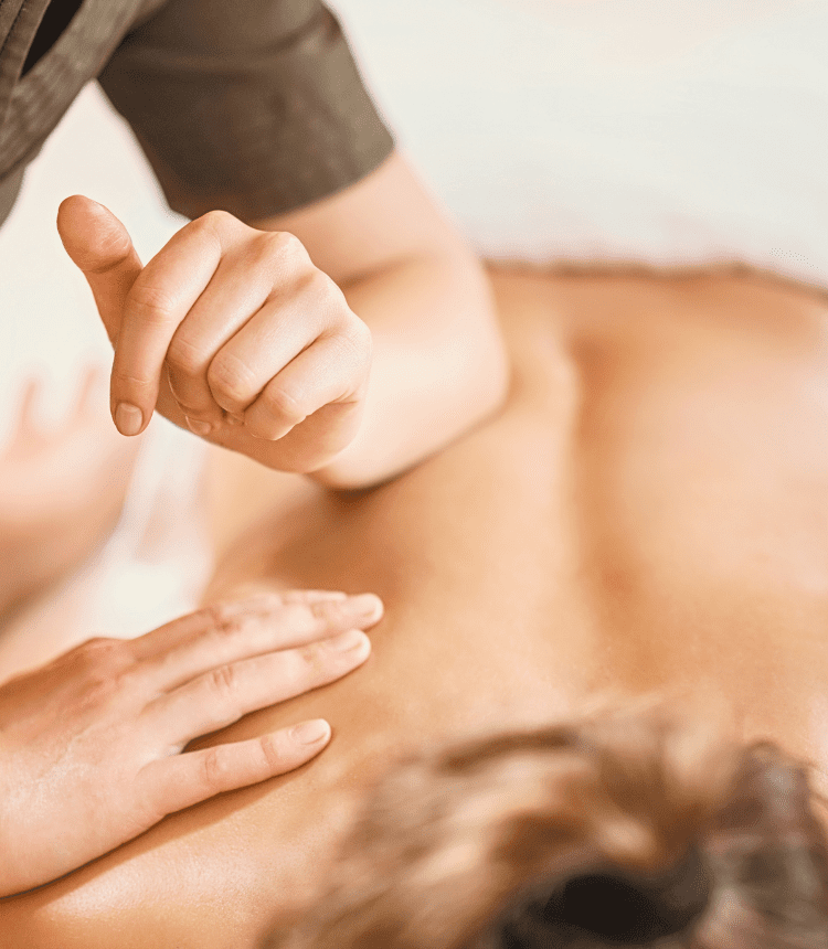 Terapista lavora sui muscoli paravertebrali con l’ausilio del gomito durante un trattamento miofasciale per alleviare dolori lombari e dorsali