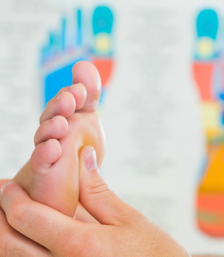 Mano che applica una pressione mirata su un punto riflesso del piede durante una seduta di riflessologia plantare